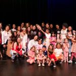 Approximately 30 dance students and teachers posing on a stage.