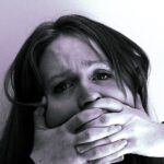 Closeup of woman looking upset with her hands covering her mouth