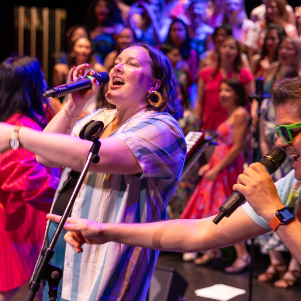 Smiling singers in front of a large choir