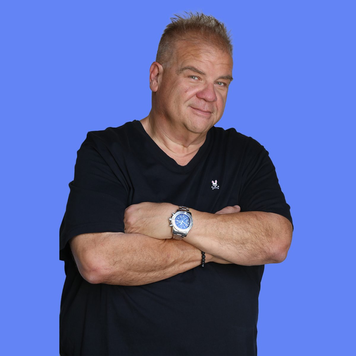 A man in a black short sleeved shirt with his arms crossed
