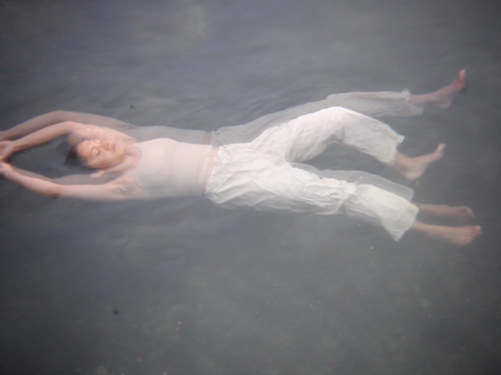 Blurred photo of dancer in light coloured clothing floating on their back