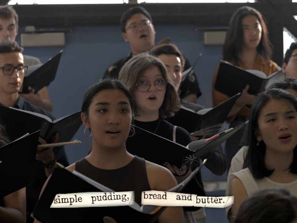 a youth choir singing while holding open black music folders